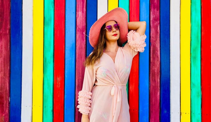 A woman in a pink dress posing in front of a colorful wall.