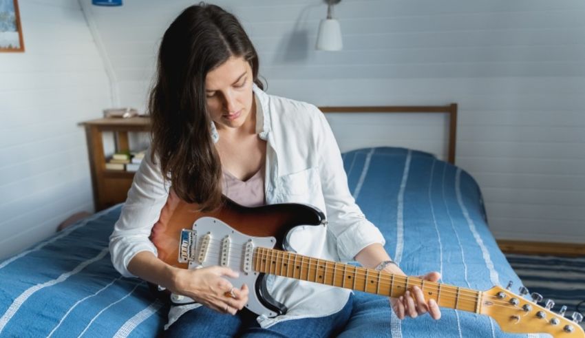 A young woman playing an electric guitar in her bedroom.