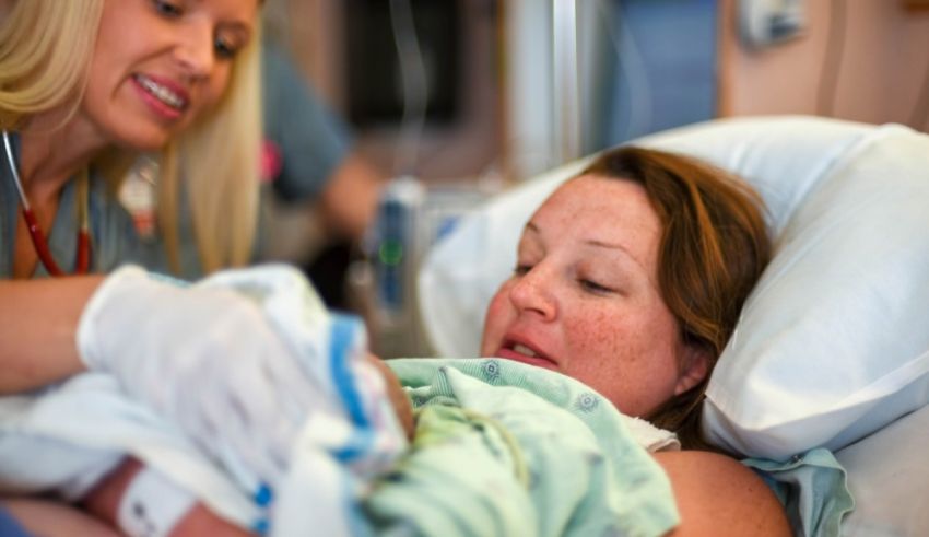 A woman is holding a baby in a hospital bed.