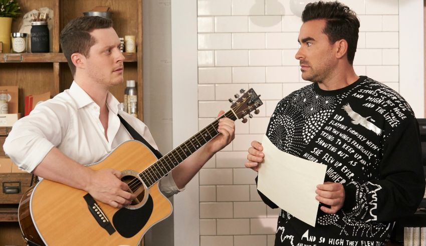 Two men standing next to each other playing an acoustic guitar.