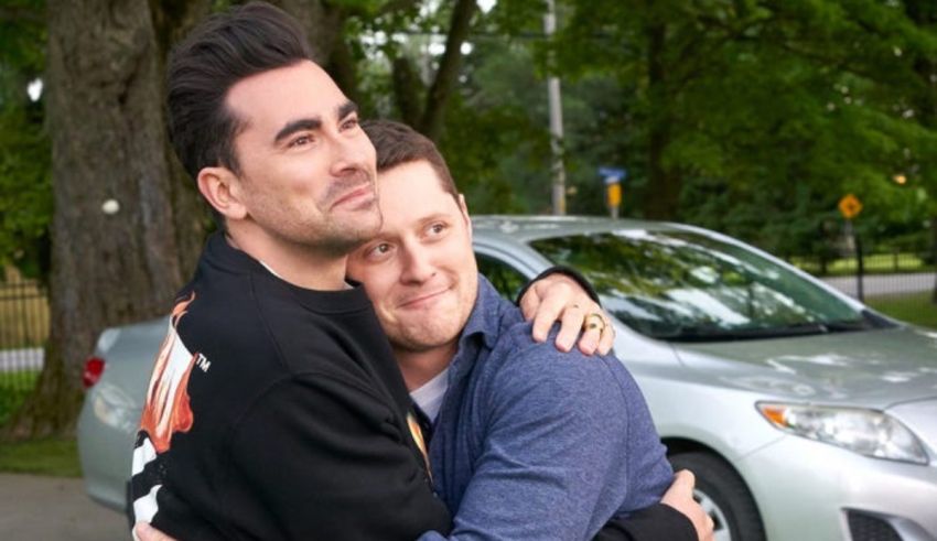 Two men hugging in front of a car.