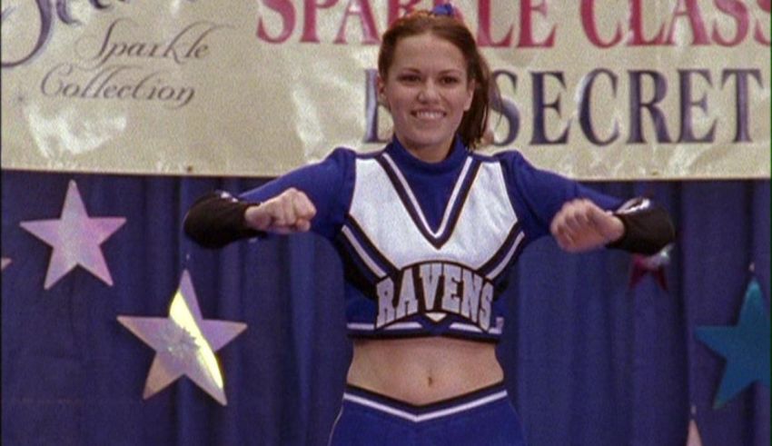 A woman in a blue cheerleader outfit is posing for the camera.