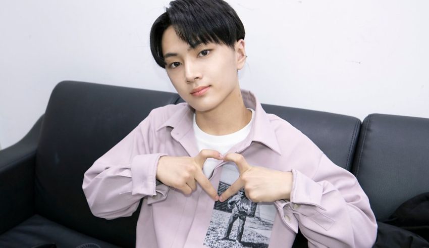 A young man making a heart sign on a couch.