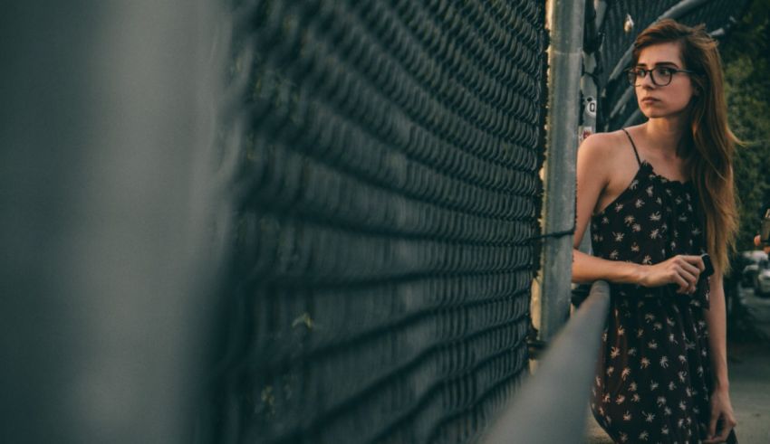 A woman leaning against a fence.