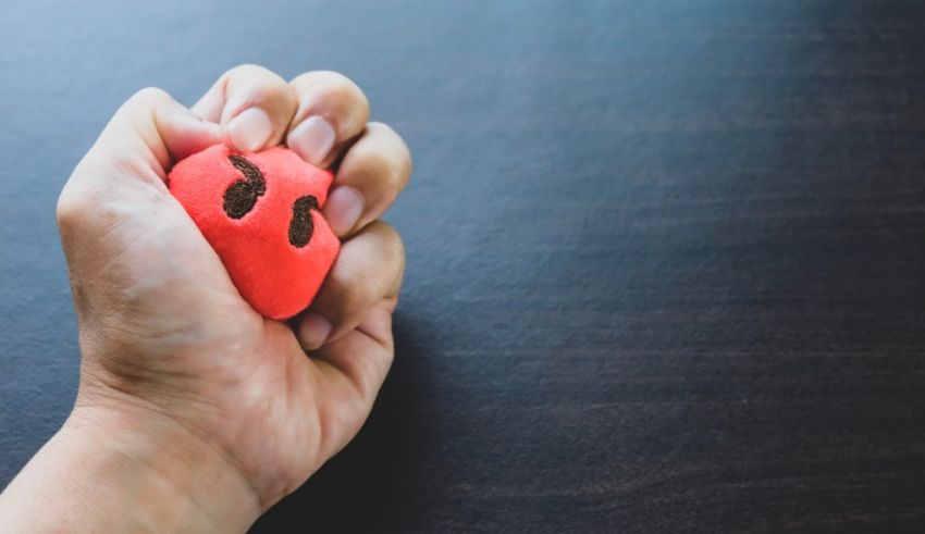 A person's hand holding a red heart shaped ball.