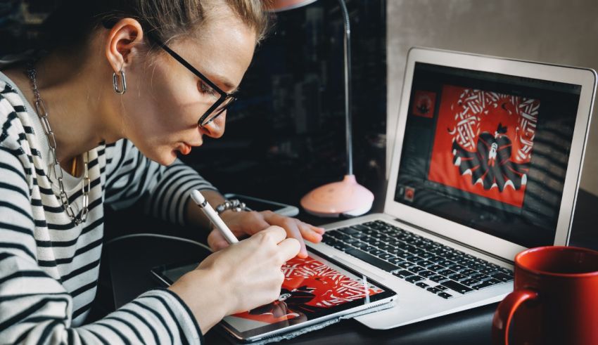 A woman working on a laptop with a pen and paper.