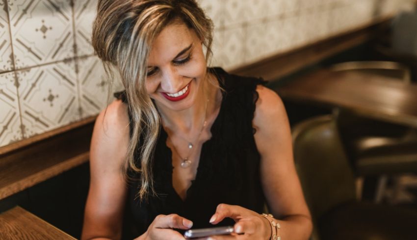 A woman looking at her phone while sitting at a table.