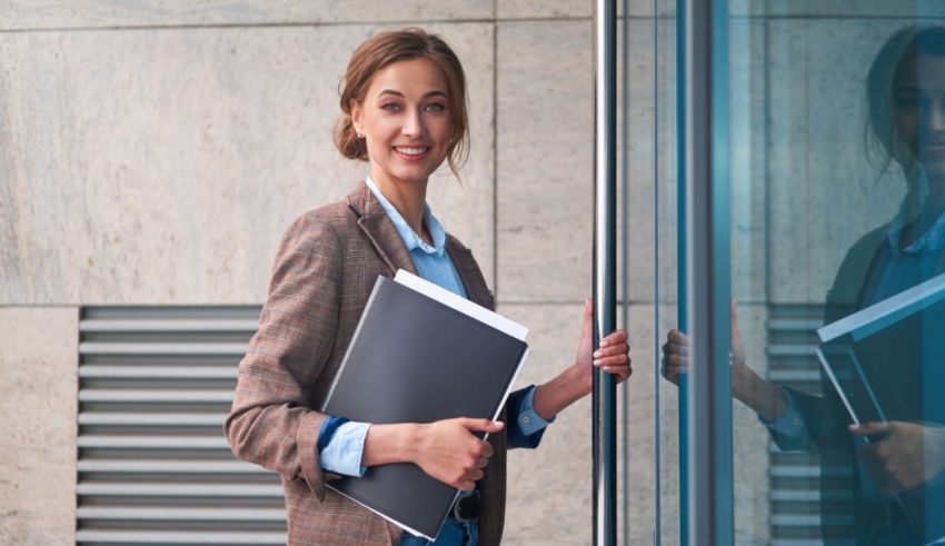 A business woman holding a folder in front of a glass door.