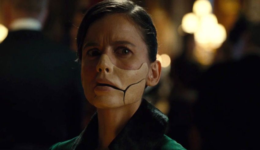 A woman in a green suit with a mask on her face.