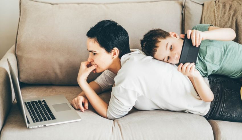 A woman and a boy lying on a couch with a laptop.