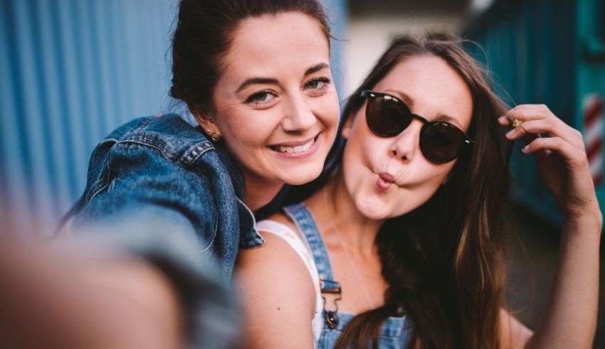 Two women are taking a selfie while wearing sunglasses.