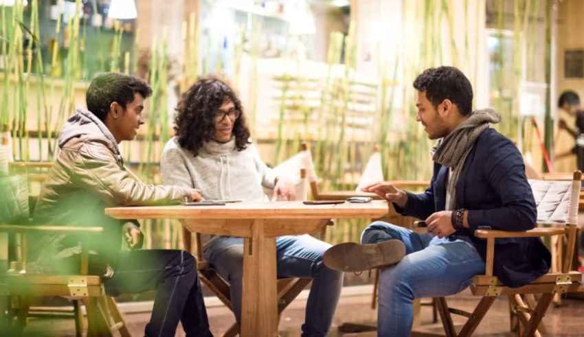 Three people sitting around a wooden table in a cafe.