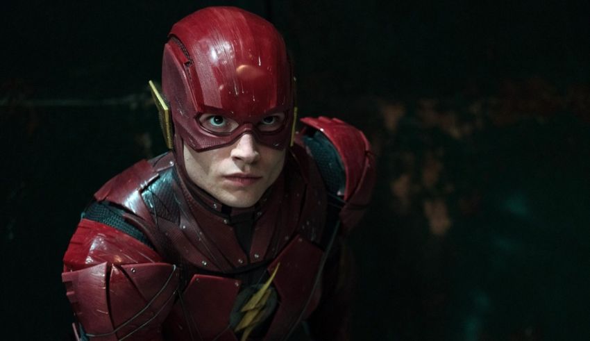 The flash in a red suit is standing in a dark room.