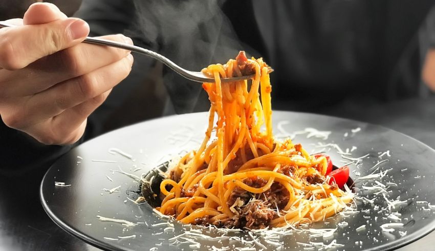 A person is holding a fork while eating spaghetti.