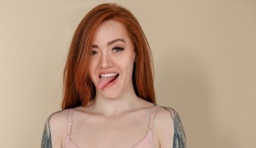 A woman with red hair and tattoos posing for a picture.