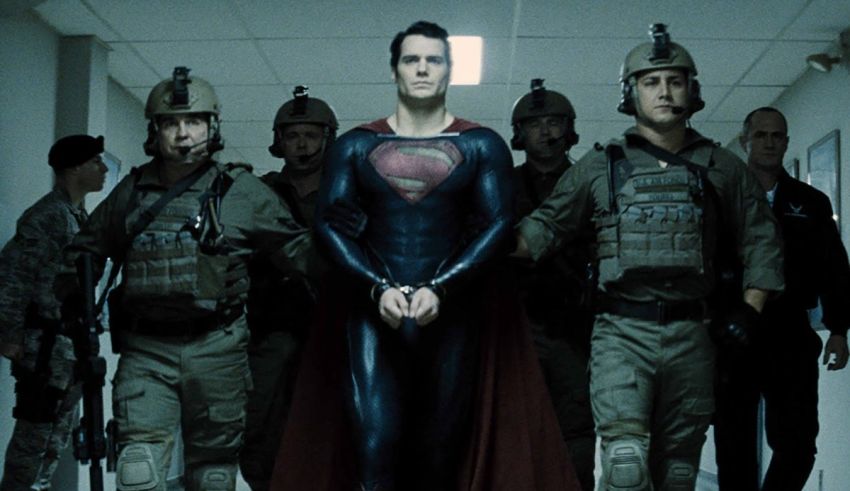 A man in a superman costume is standing in front of a group of soldiers.