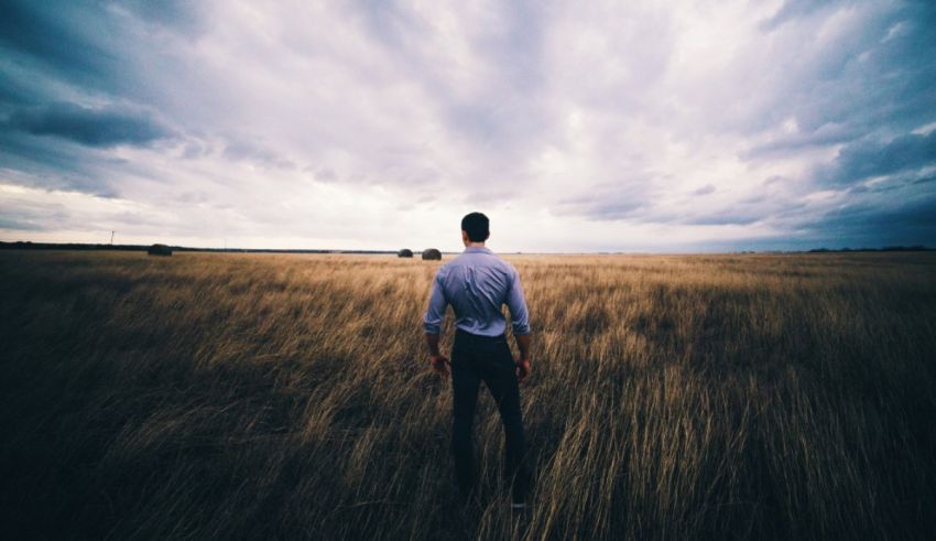 A man standing in a field under a cloudy sky.