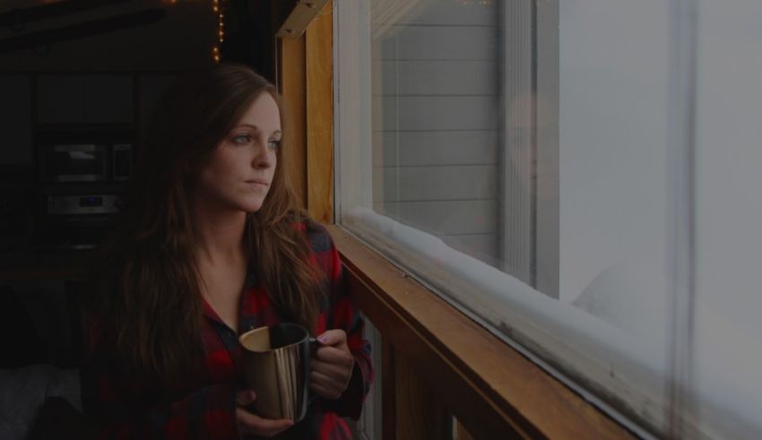 A woman looking out a window with a cup of coffee.