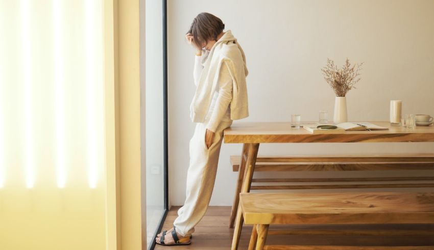 A woman leaning against a wooden table in a room.