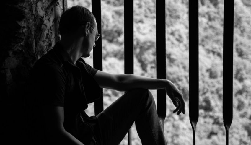 A black and white photo of a man looking out of a window.