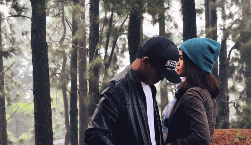 A man and woman are standing in a wooded area.