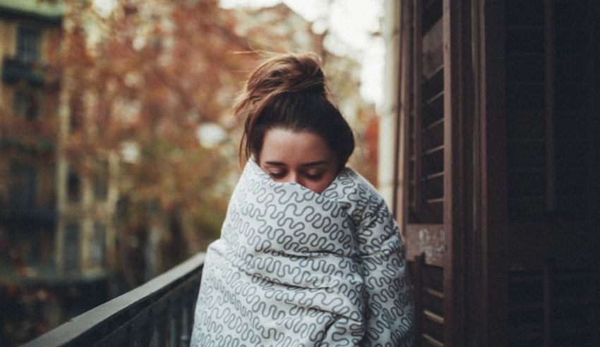 A woman wrapped in a blanket on a balcony.