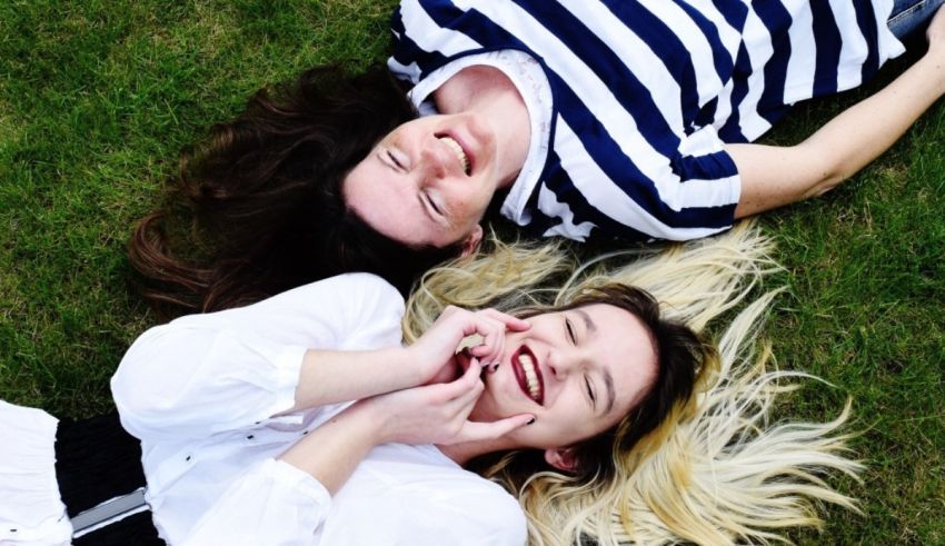Two women laying on the grass laughing.