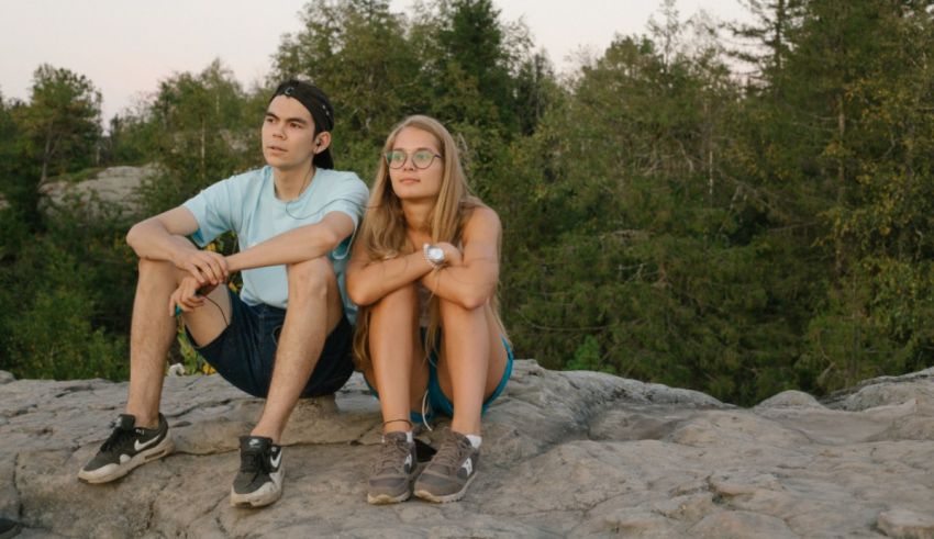 A young couple sitting on a rock in the forest.