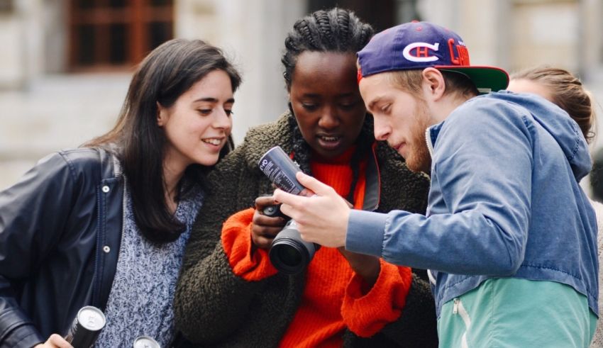 A group of young people looking at a cell phone.