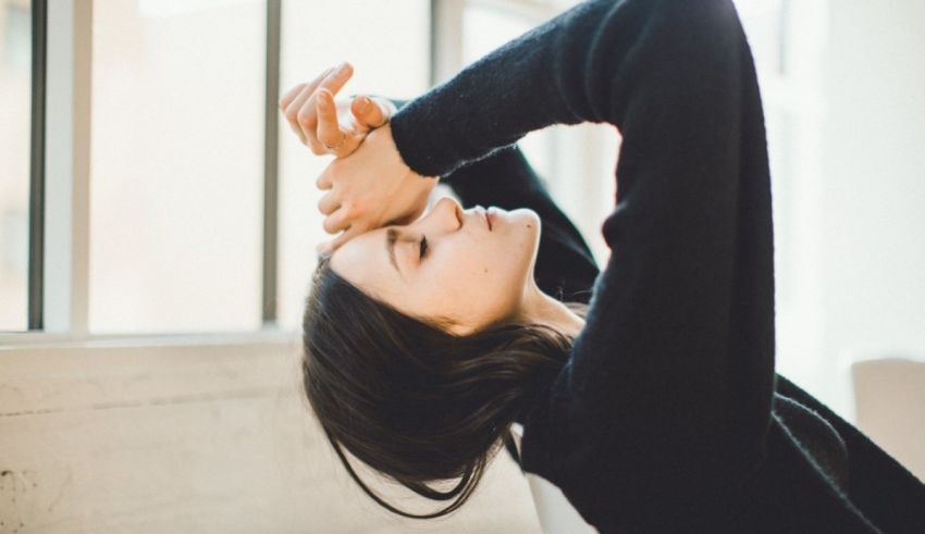 A woman stretching her head in front of a window.