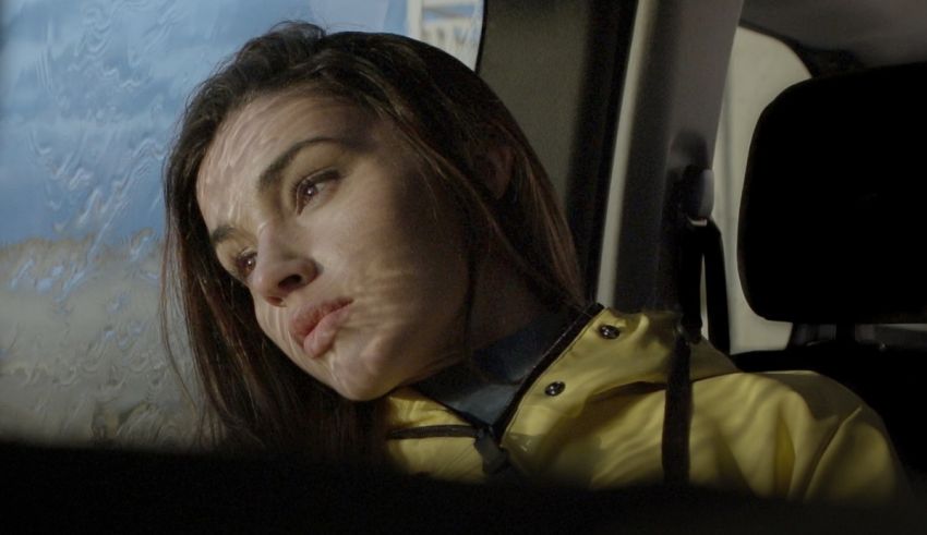 A woman in a yellow jacket sitting in a car.