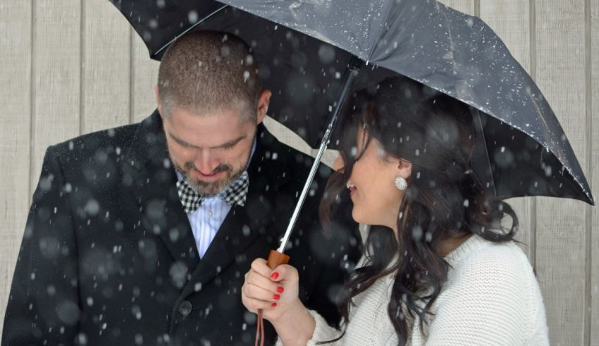 A man and woman standing under an umbrella in the snow.