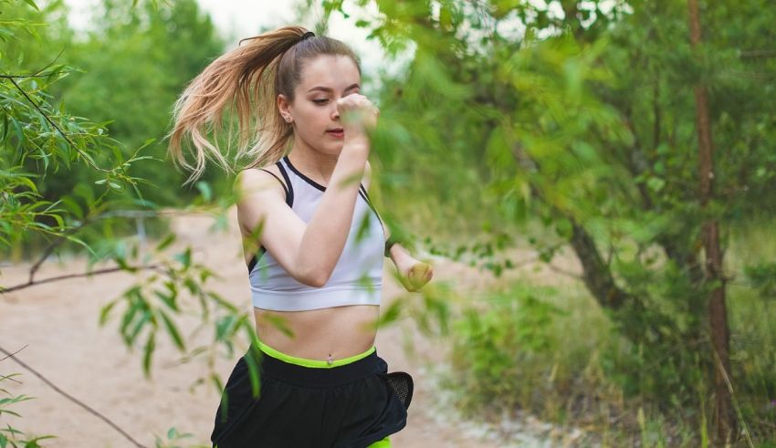 A woman jogging through a forest.