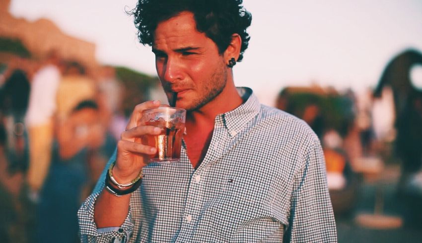 A man drinking from a glass at an outdoor event.