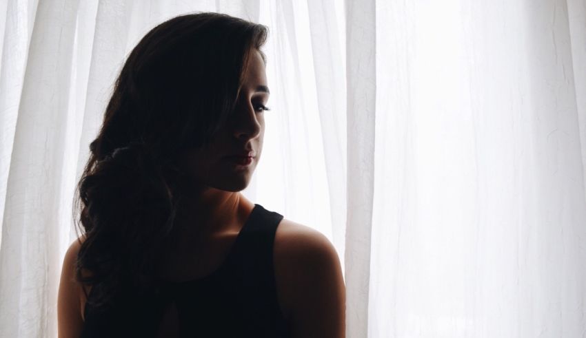 A woman in a black dress standing in front of a curtain.