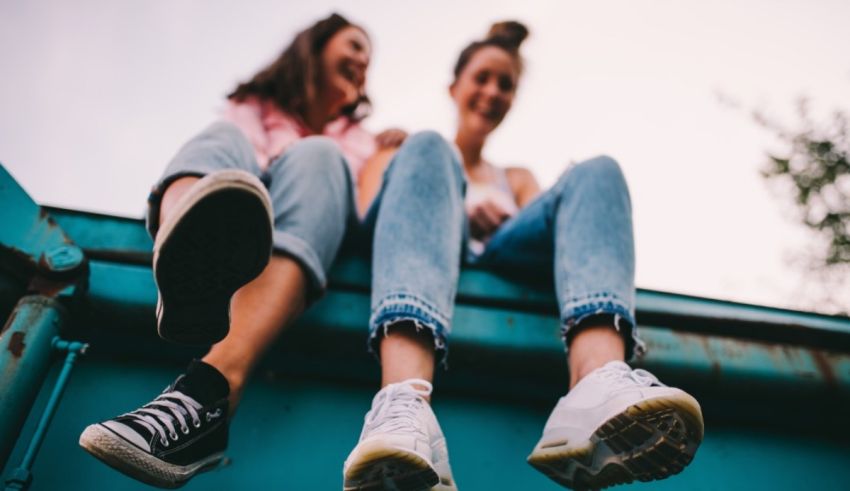 Two girls sitting on top of a blue truck.