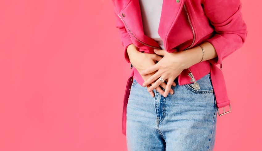 A woman is holding her stomach on a pink background.