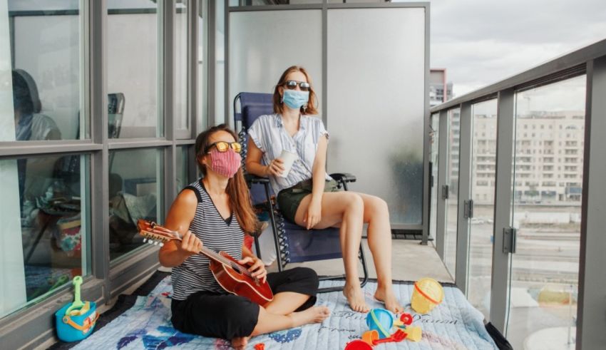 Two women wearing face masks on a balcony.