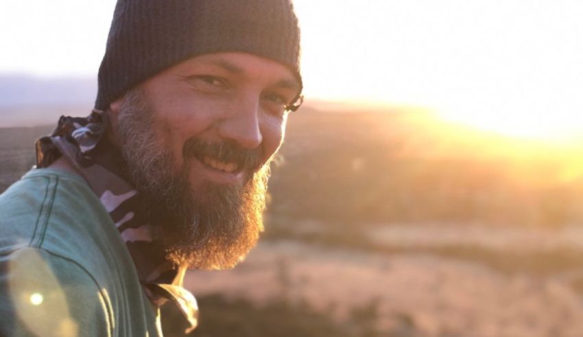 A man with a beard smiling at the sunset.