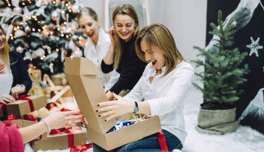 A group of women are opening gifts in front of a christmas tree.