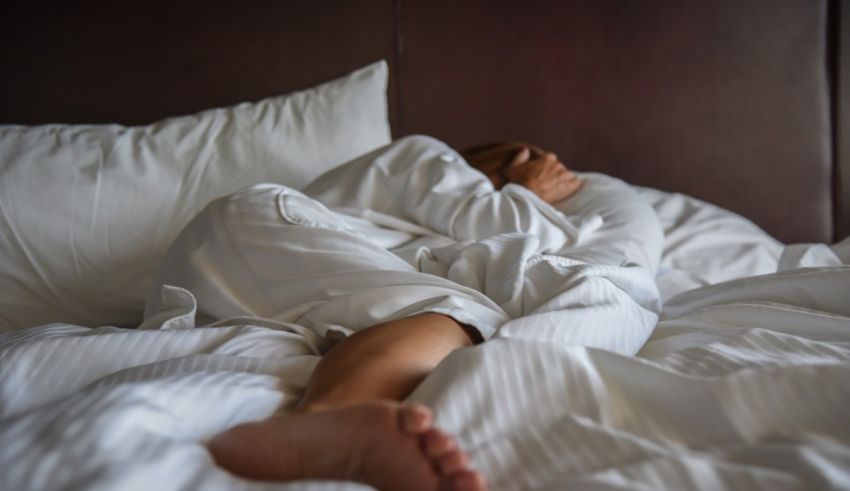 A person is sleeping in a bed with white sheets.