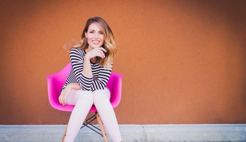 A woman sitting on a pink chair.