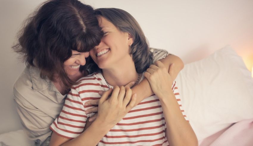 Two women hugging each other in bed.