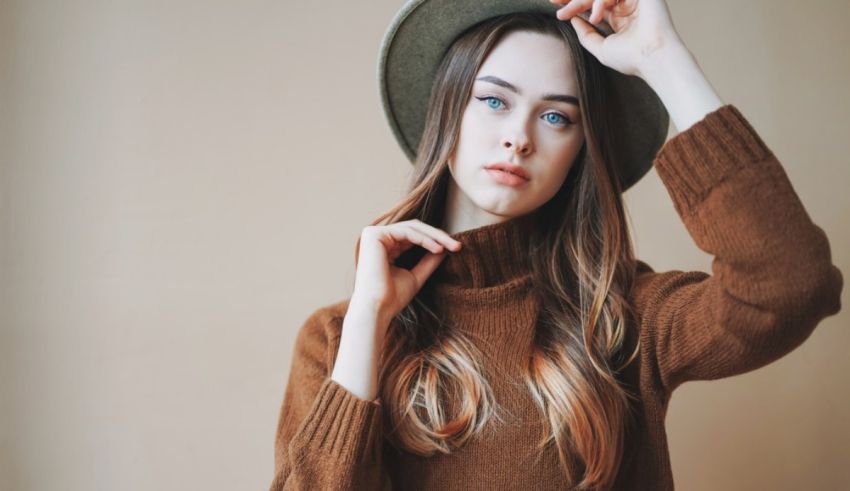 A young woman wearing a brown sweater and a hat.