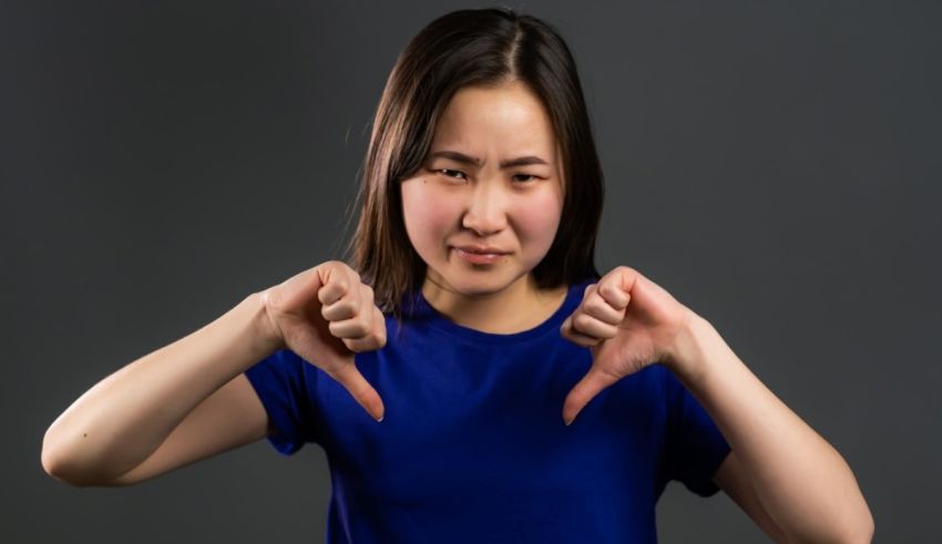 A young asian woman showing her thumbs down.