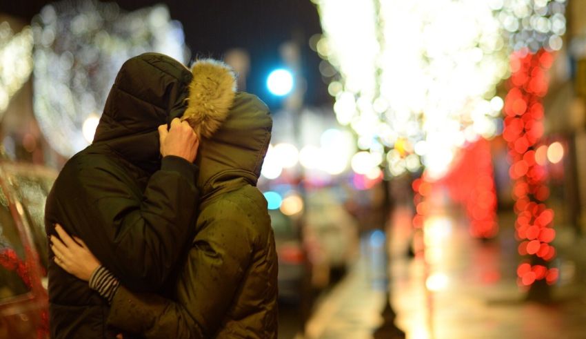A couple hugging in front of christmas lights.