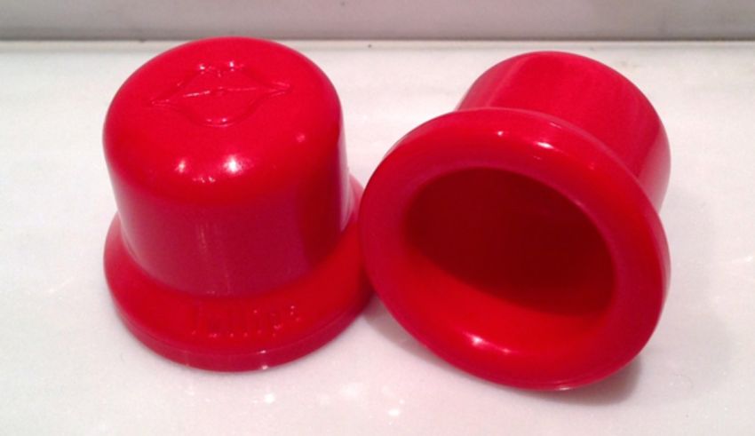 A pair of red plastic lids on a white surface.