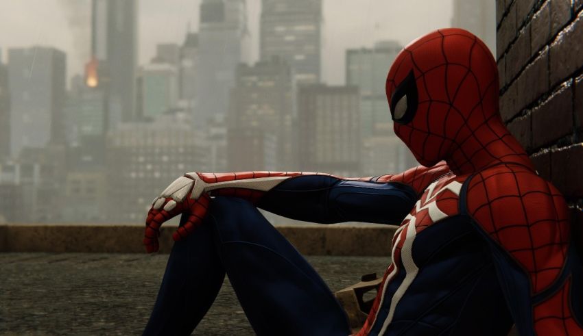 A spider - man sitting on a wall in front of a city.