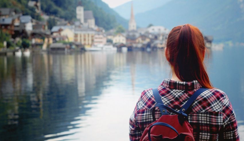 A woman looking out over a lake with a backpack.