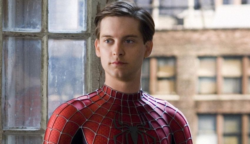 A young man in a spider - man suit is standing in front of a window.